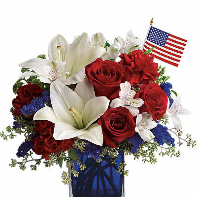 Red roses and white lilies in a blue vase with a small American flag