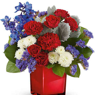Red roses, white mums, and blue flowers in a red vase