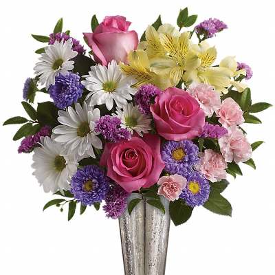 Mixed bouquet of pink roses, daisies, and purple flowers in a silver vase