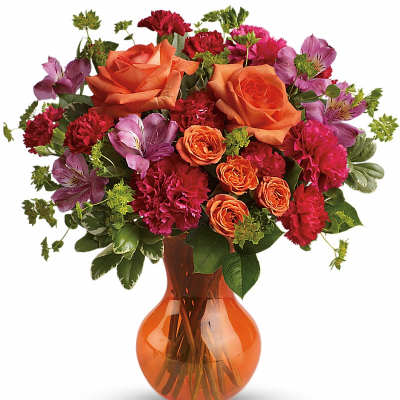 Orange roses and pink flowers arranged in an orange glass vase