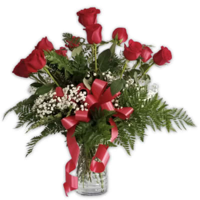 Red roses in a glass vase with baby's breath and a red ribbon