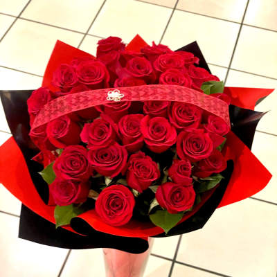 Bouquet of red roses wrapped in red and black paper in a clear vase