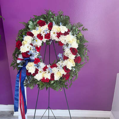 Circular floral wreath on a stand with red, white, and blue flowers