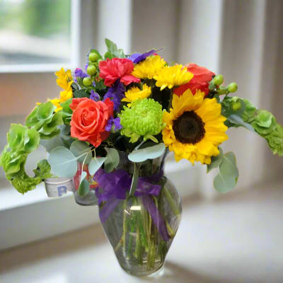 Colorful bouquet with sunflowers, roses, and chrysanthemums in a glass vase