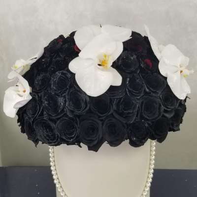Black rose arrangement with white orchids in a white vase