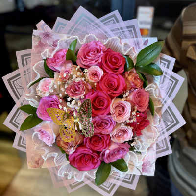 Pink and red rose bouquet with decorative wrapping and a butterfly accent