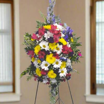 Standing floral spray with mixed bright flowers on a metal easel