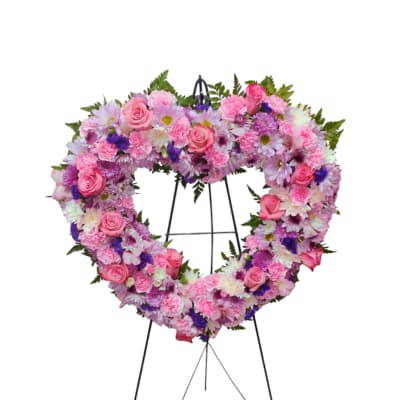 Heart-shaped pink and purple floral wreath on a black stand