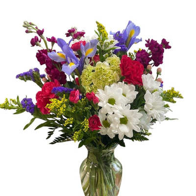 Mixed bouquet of purple, white, pink, and yellow flowers in a glass vase