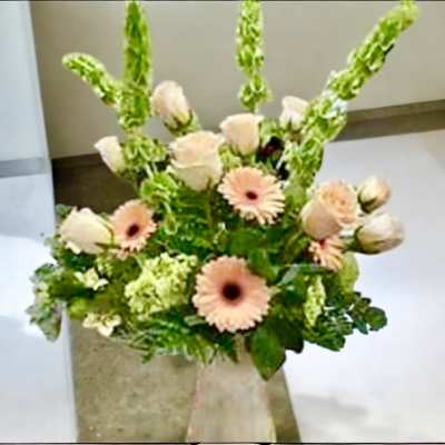 Peach gerbera daisies and pale roses in a clear vase