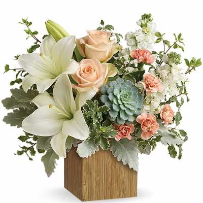 Bouquet of white lilies, peach roses, and carnations in a wooden cube vase