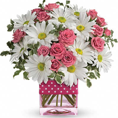 Pink roses and white daisies arranged in a pink glass vase with polka dots