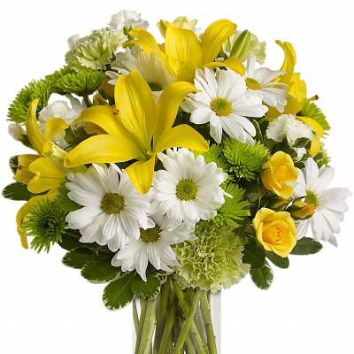 Yellow lilies and white daisies in a clear glass vase