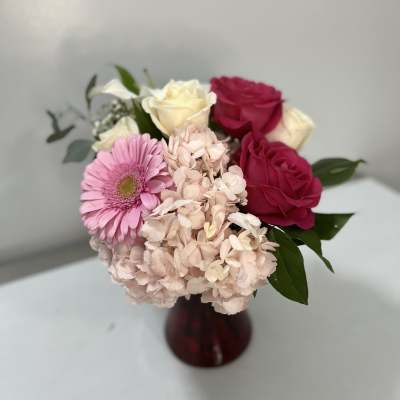 Pink and white bouquet with roses and hydrangeas in a burgundy vase