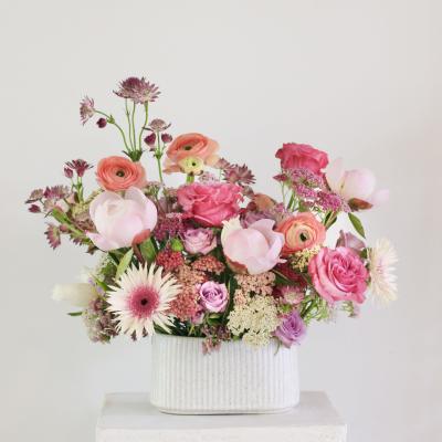 Pink and peach mixed flowers in a white ribbed vase