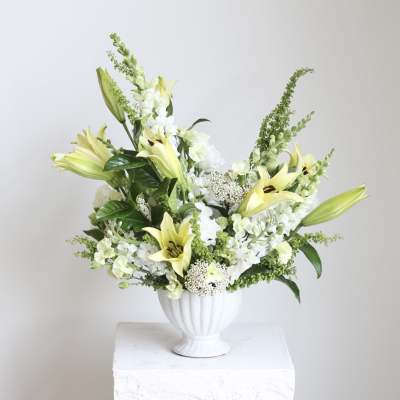 White and pale yellow lily arrangement in a white vase