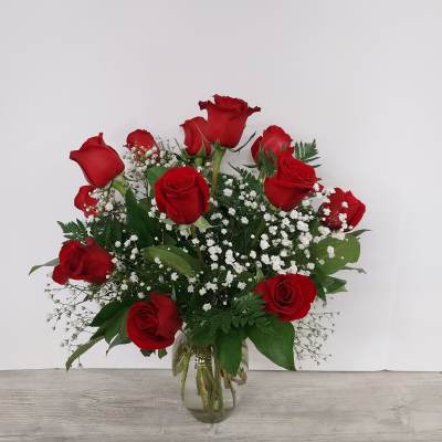 Arrangement of red roses with white filler flowers in a clear glass vase