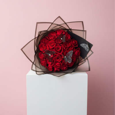Bouquet of red roses wrapped in black paper with butterfly accents