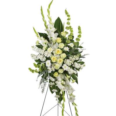 Tall white and pale yellow funeral spray on a stand