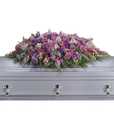 Lavender and pink floral casket spray on a gray casket