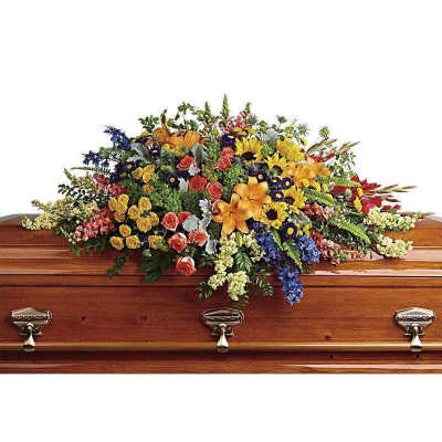 Colorful casket spray with mixed flowers on a wooden coffin