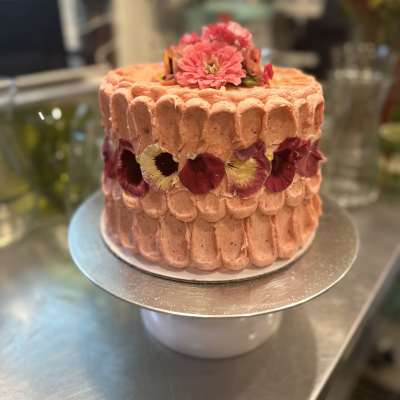 Pink frosted cake decorated with edible flowers