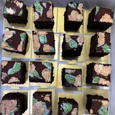 Square chocolate cakes topped with pastel floral frosting on gold boards