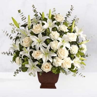 White lilies and cream roses arranged in a brown urn vase