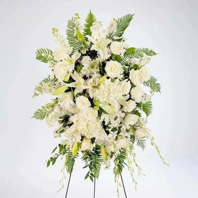White floral standing spray with roses and lilies on a stand