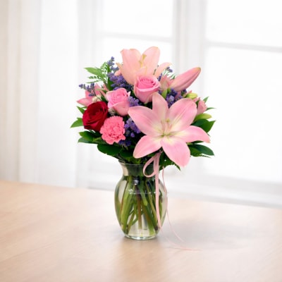 Pink lilies and roses arranged in a glass vase