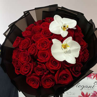 Bouquet of red roses with two white orchids wrapped in black paper
