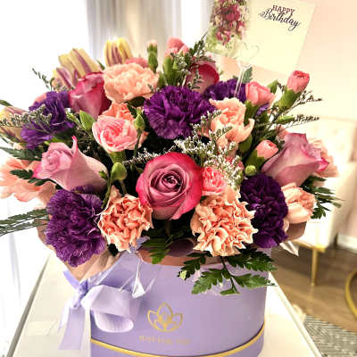 Pink and purple mixed bouquet in a lavender gift box with a birthday card