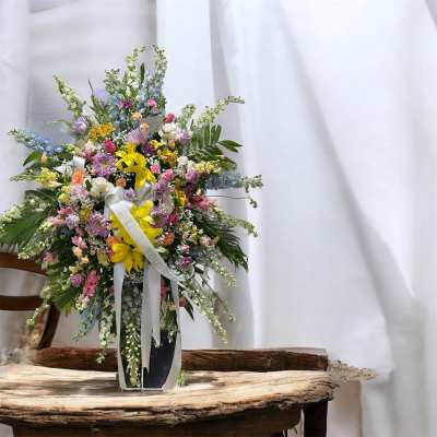 Large mixed flower arrangement in a tall vase with white ribbons