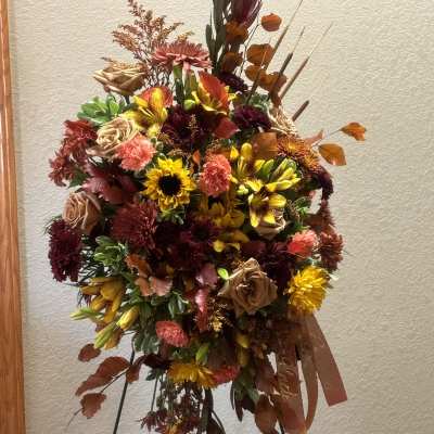 Large autumn floral spray on a stand with sunflowers, roses, and mums