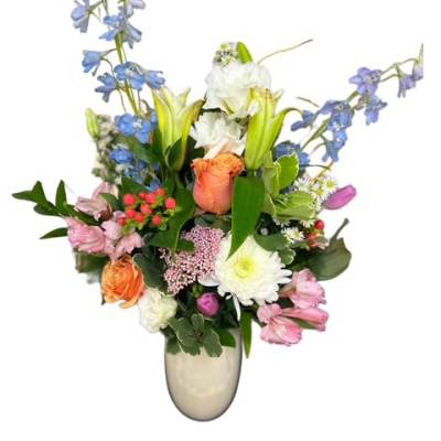 Mixed bouquet of blue, pink, white, and orange flowers in a silver vase