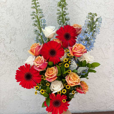 Mixed bouquet in a beige vase with red gerberas and peach roses