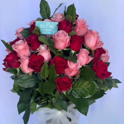 Bouquet of red and pink roses in a clear vase with a white bow