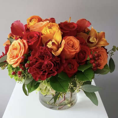 Bouquet of red and orange roses with orchids in a glass vase