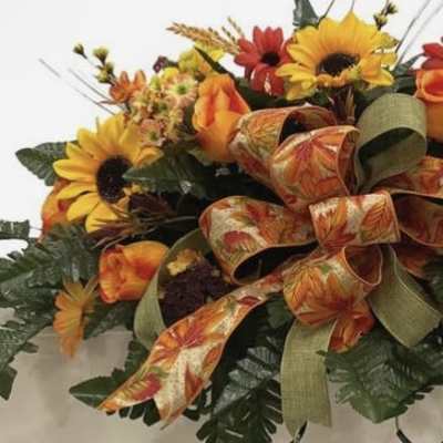 Autumn floral arrangement with sunflowers, roses, and ribbon accents