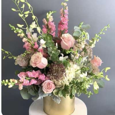 Pink and white floral arrangement in a gold cylinder vase
