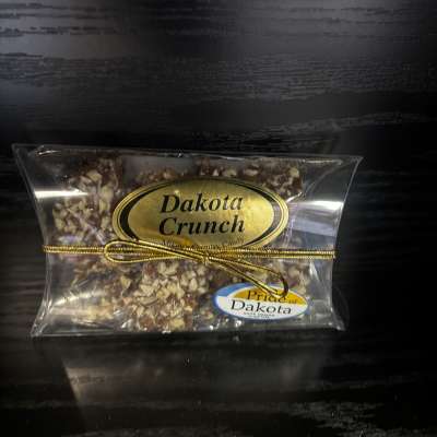 Clear bag of Dakota Crunch candy tied with a gold ribbon
