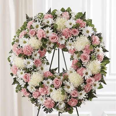 Heart-shaped floral wreath with pink and white flowers on a stand