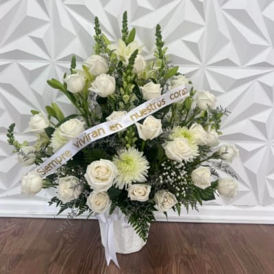 White rose and lily arrangement in a white basket with a ribbon