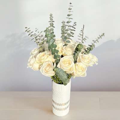White rose bouquet in a patterned vase with eucalyptus stems