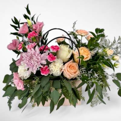 Pink and peach floral arrangement in a handled basket