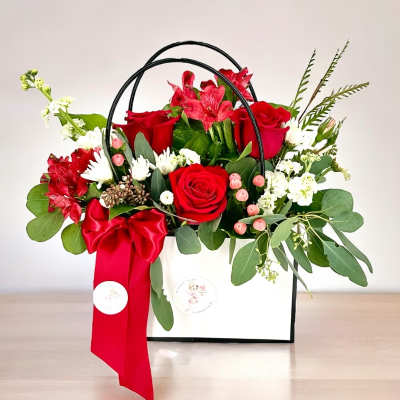 Red roses and white flowers in a white gift box with a red ribbon
