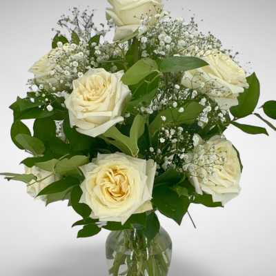 Cream roses arranged in a clear glass vase with baby's breath