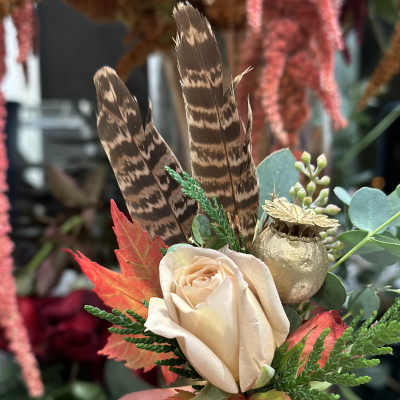 Cream rose with feathers, autumn leaves, and a gold pod accent