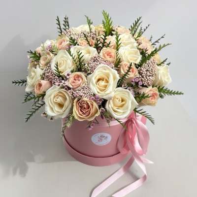 Bouquet of cream and blush roses in a pink hatbox with ribbon
