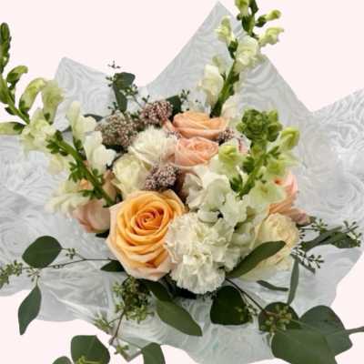 Bouquet of peach roses and white flowers wrapped in patterned paper